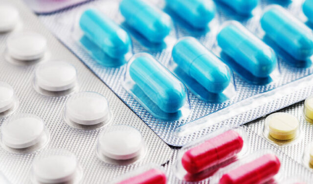 Heap of medical pills in white, blue and other colors. Pills in plastic package. Concept of healthcare and medicine.